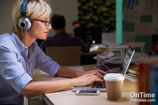 Female Office Worker With Coffee At Desk Working Late